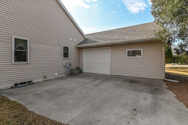 view of side of property featuring an attached garage, concrete driveway, and roof with shingles