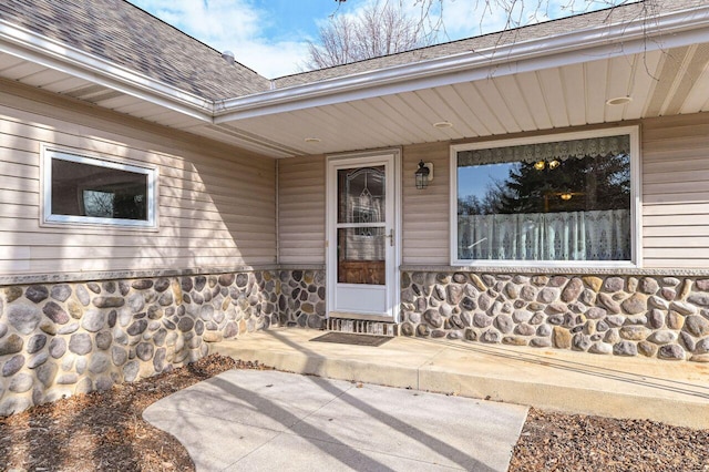 entrance to property with stone siding and roof with shingles