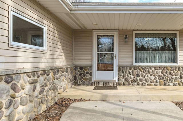 entrance to property featuring covered porch and stone siding