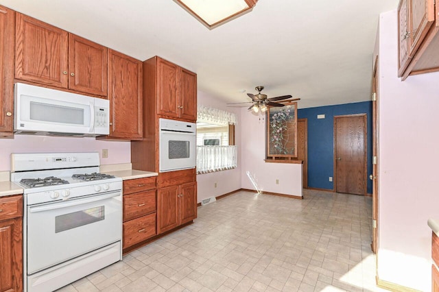 kitchen with baseboards, white appliances, brown cabinetry, and light countertops