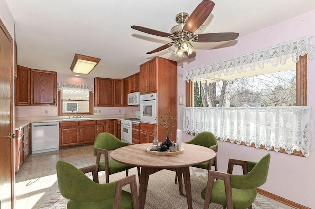 kitchen with light countertops, brown cabinets, white appliances, a ceiling fan, and a sink