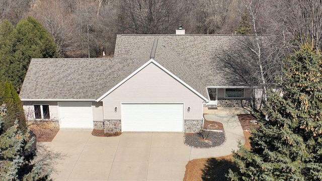 view of front of house with driveway, a shingled roof, a chimney, a garage, and stone siding