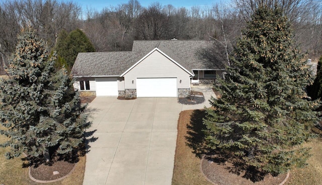 view of front facade with concrete driveway, an attached garage, and stone siding