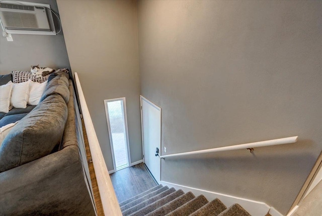 stairs featuring an AC wall unit, wood finished floors, and baseboards