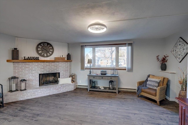 living area featuring a fireplace, wood finished floors, baseboard heating, and a textured ceiling