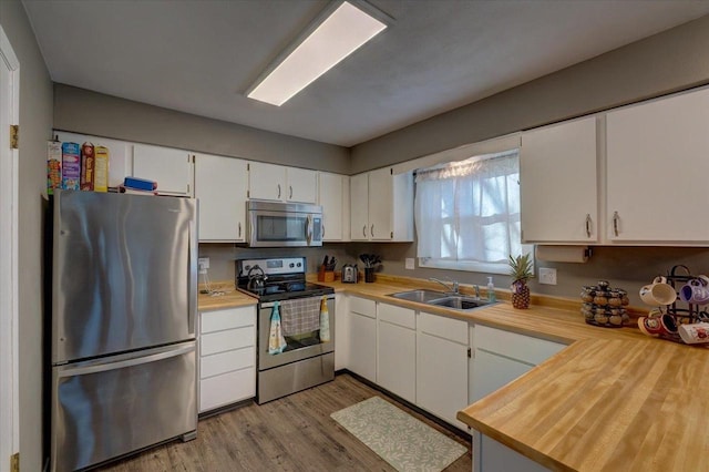 kitchen with a sink, white cabinetry, appliances with stainless steel finishes, and light countertops