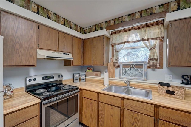 kitchen featuring under cabinet range hood, stainless steel electric stove, brown cabinets, and a sink