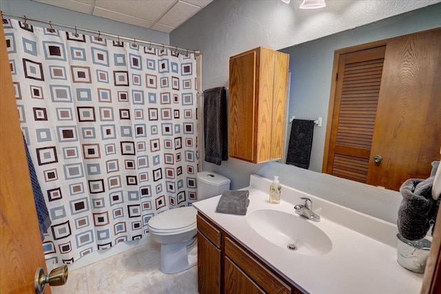 full bath featuring vanity, a shower with curtain, a drop ceiling, tile patterned floors, and toilet