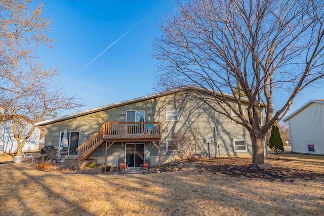 rear view of property featuring a yard, stairway, and a deck