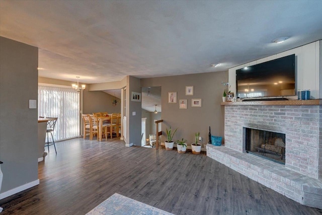 unfurnished living room with a fireplace, wood finished floors, baseboards, and a chandelier