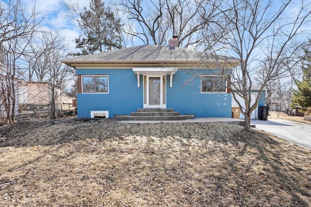 view of front of property featuring a shingled roof, fence, entry steps, stucco siding, and a chimney