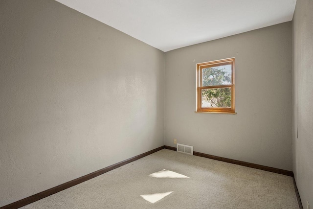 empty room featuring visible vents, carpet floors, and baseboards