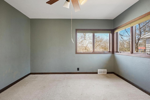 carpeted empty room with visible vents, baseboards, and a ceiling fan