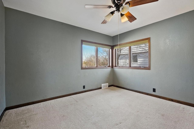 carpeted empty room featuring visible vents, baseboards, ceiling fan, and a textured wall