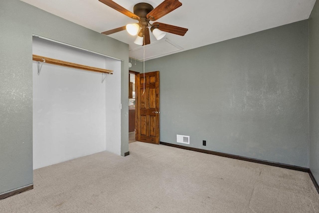 unfurnished bedroom with visible vents, ceiling fan, carpet, attic access, and a closet