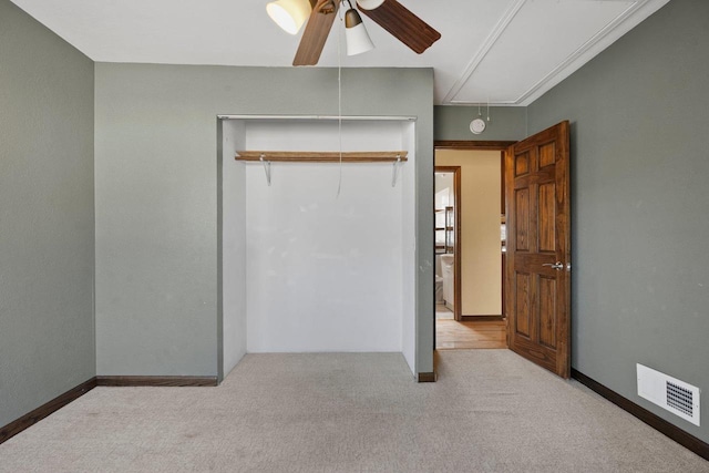 unfurnished bedroom with visible vents, carpet, attic access, and a closet