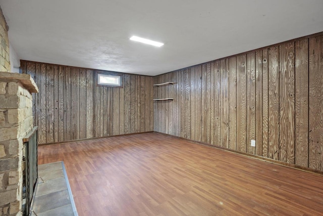 basement featuring a fireplace, wooden walls, and wood finished floors