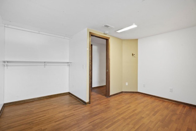 unfurnished bedroom featuring a closet, visible vents, baseboards, and wood finished floors