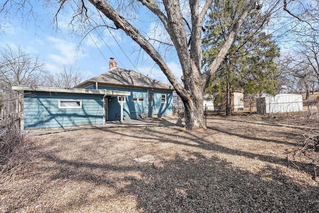 back of house with a chimney and fence