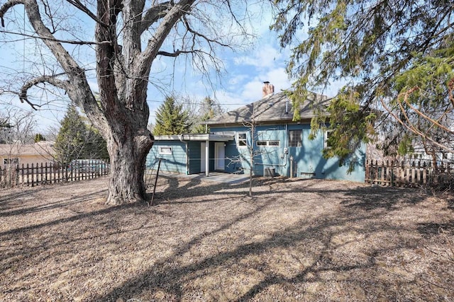 back of property with a chimney and fence