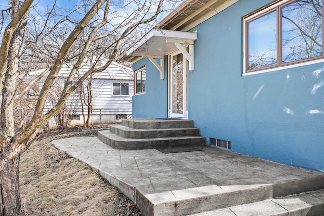 property entrance with visible vents and stucco siding