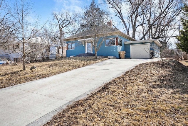 bungalow-style house featuring a garage, a chimney, and driveway