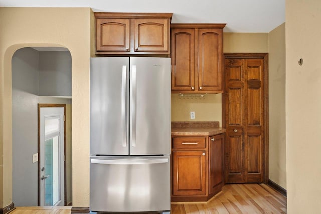 kitchen with brown cabinets, light wood-type flooring, and freestanding refrigerator