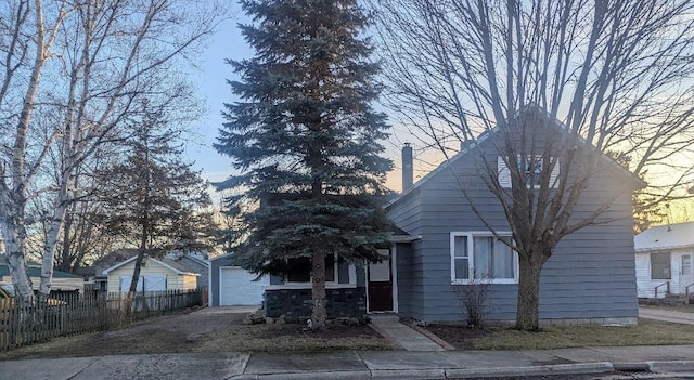 view of front of property featuring concrete driveway, a chimney, and fence