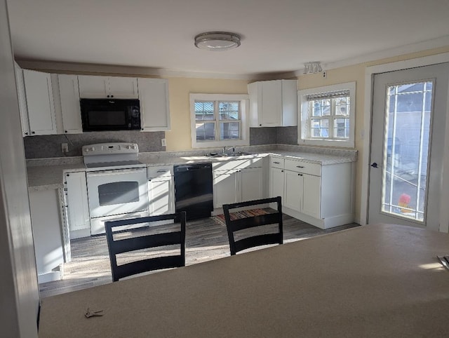 kitchen with tasteful backsplash, black appliances, white cabinets, and light countertops