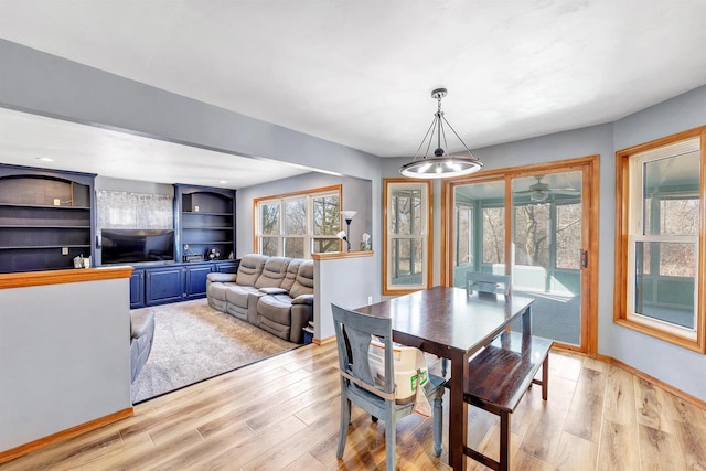 dining area featuring light wood finished floors, baseboards, and an inviting chandelier