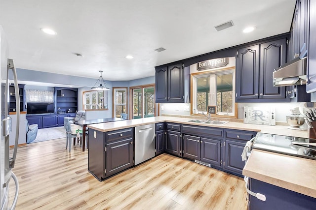 kitchen with under cabinet range hood, light countertops, a peninsula, stainless steel appliances, and a sink