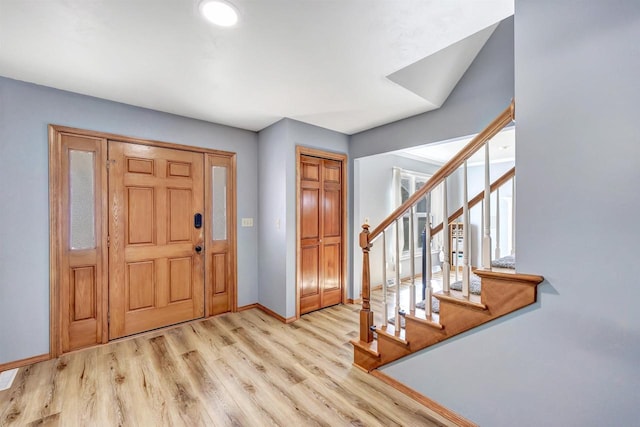 foyer featuring light wood-type flooring, stairs, and baseboards