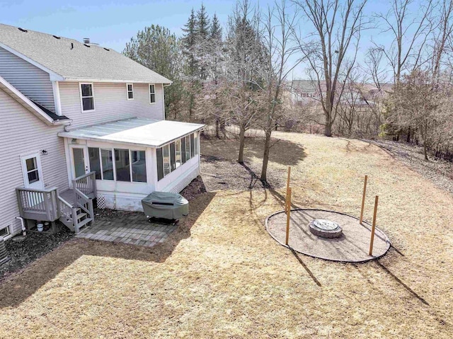 rear view of house with a fire pit and a sunroom