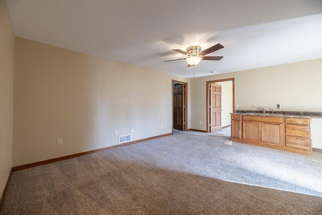 5628 E Eagle Dr, Milton, WI 53563 - empty room with a ceiling fan, visible vents, baseboards, a sink, and light colored carpet