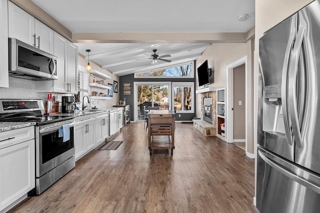 kitchen with backsplash, lofted ceiling with beams, appliances with stainless steel finishes, white cabinetry, and a sink