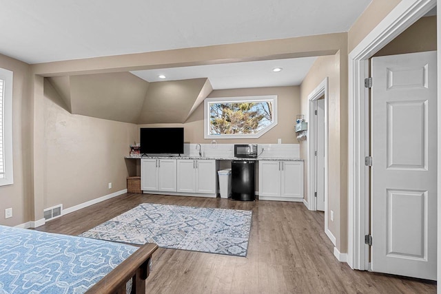 kitchen featuring light wood finished floors, visible vents, white cabinets, and black microwave