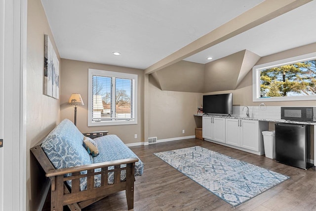 living area featuring visible vents, a healthy amount of sunlight, baseboards, and wood finished floors