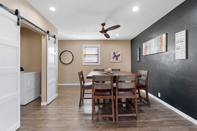 dining space featuring light wood finished floors, ceiling fan, baseboards, and a barn door