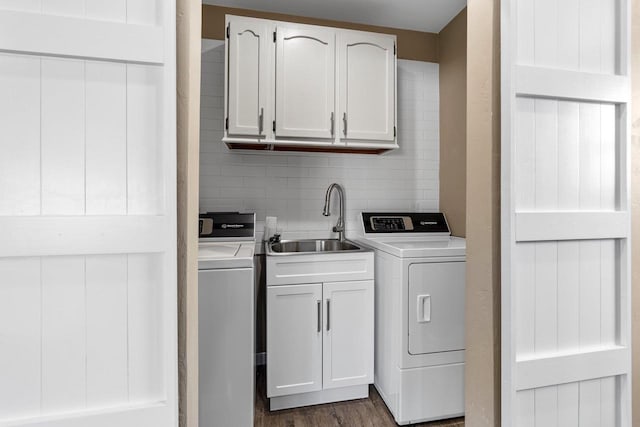 clothes washing area featuring dark wood-type flooring, washing machine and clothes dryer, cabinet space, and a sink