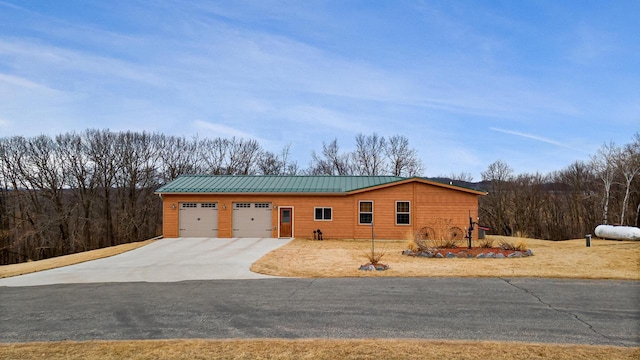 view of front facade with a standing seam roof, concrete driveway, an attached garage, and metal roof