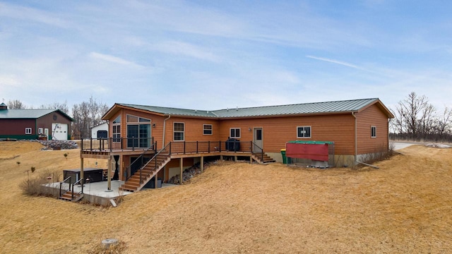 rear view of house featuring a wooden deck, stairway, a patio area, and metal roof