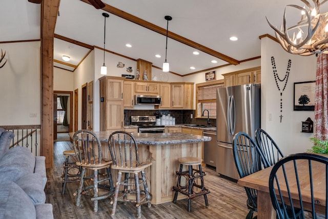 kitchen featuring light brown cabinets, a sink, wood finished floors, stainless steel appliances, and vaulted ceiling with beams