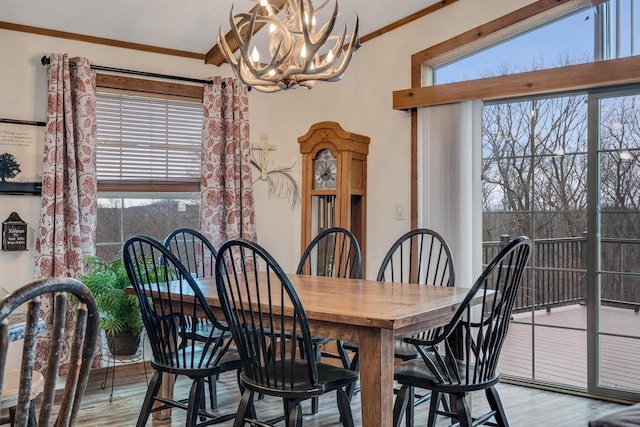 dining area featuring plenty of natural light, crown molding, light wood-style floors, and an inviting chandelier