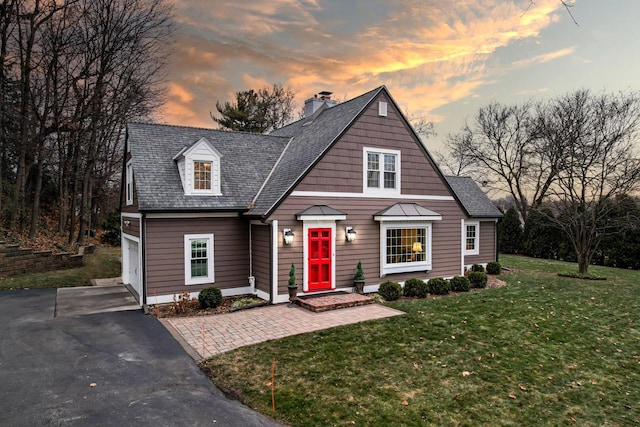 view of front of home with a front lawn, aphalt driveway, roof with shingles, a garage, and a chimney