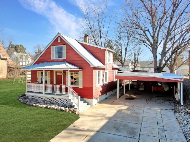 view of front of home with a front yard, driveway, covered porch, a chimney, and metal roof