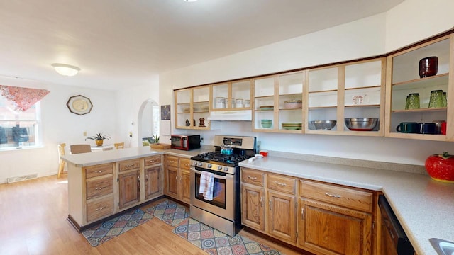 kitchen featuring visible vents, under cabinet range hood, a peninsula, arched walkways, and black appliances