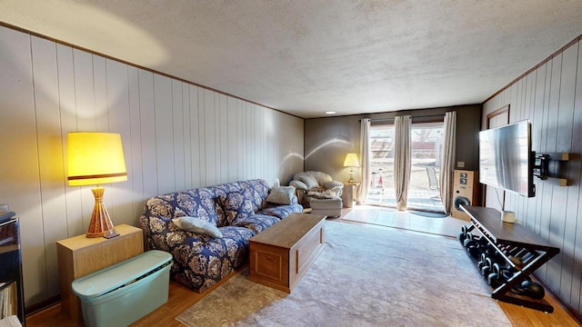 living area featuring ornamental molding, a textured ceiling, and wood finished floors