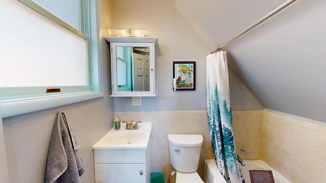 full bath featuring shower / tub combo with curtain, toilet, tile walls, vanity, and vaulted ceiling