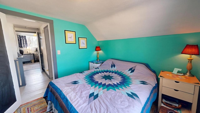 bedroom with wood finished floors and vaulted ceiling