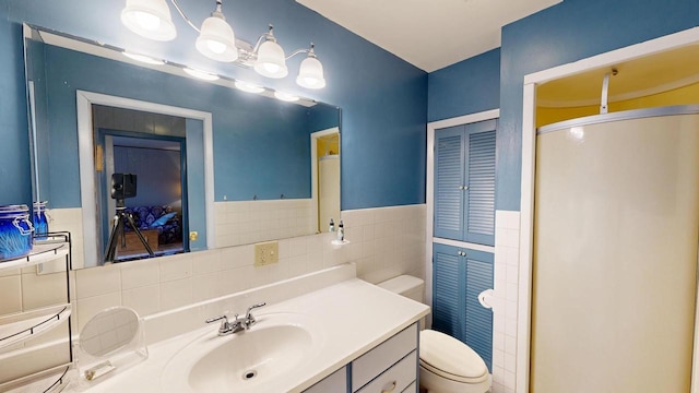 full bath featuring a shower stall, tile walls, toilet, wainscoting, and vanity